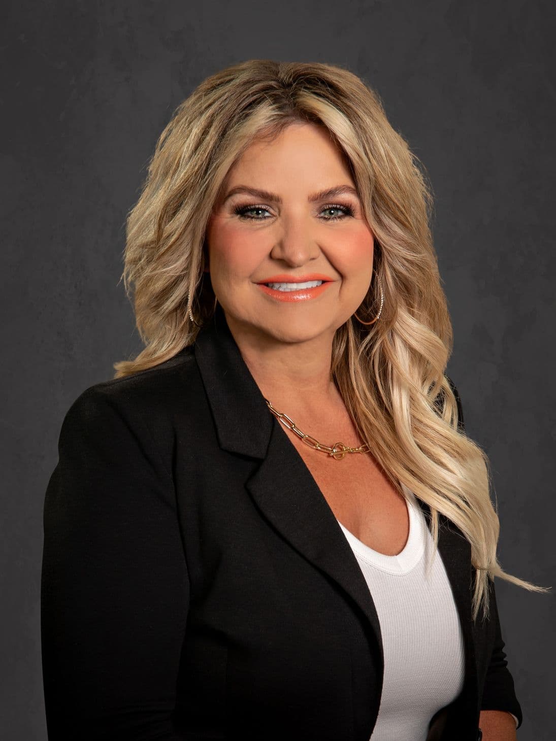Professional woman with blonde hair smiling in black blazer.